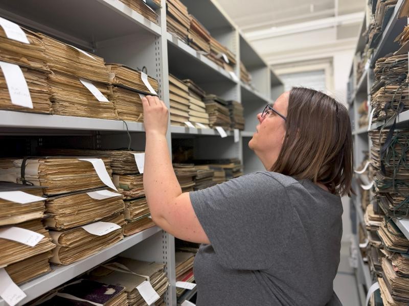 Eine Frau steht an einem Archivregal