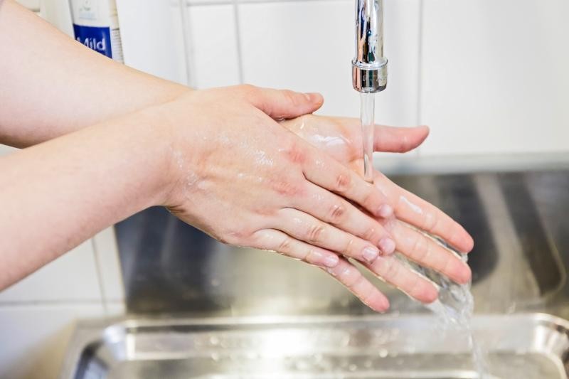 Hände werden unter einem Wasserhahn mit fließendem Wasser gewaschen.