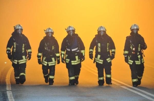 Fünf Feuerwehrleute laufen auf die Blickperspektive zu.