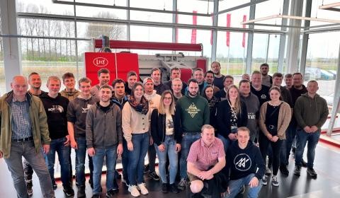 Männer und Frauen posieren aufgereiht vor einer Fensterfront für ein Gruppenfoto