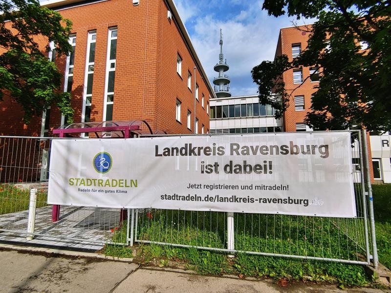 Stadtradeln Vor einem Backsteinverwaltungsgebäude steht auf der Wiese davor ein Banner mit der Aufschrift Stadtradeln und Landkreis Ravensburg ist dabei.