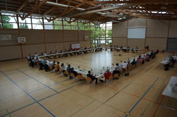 Besprechungsrunde aus Vertretern der Wirtschaft, Gesellschaft und Politik in einer Sporthalle.