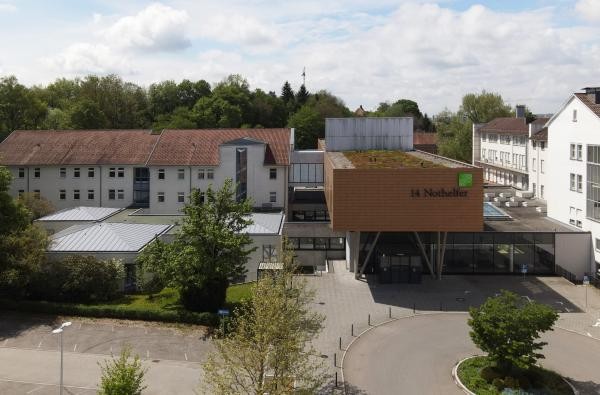 Neue Unterbringungen links mehrstöckige Gebäude, rechts daneben ein modernes Gebäude, das das Ärztehaus darstellt.