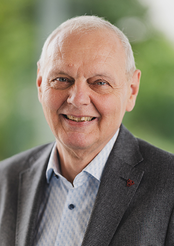 Franz Baur, ein Mann gehobenen Alters mit hoher Stirn und weißem kurzem Haar. Er trägt weder Bart noch Brille. Er trägt ein graues Jackett und darunter ein helles Hemd.
