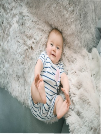 menschliches hellhäutiges Baby auf einer weichen Felltextiloberfläche liegend