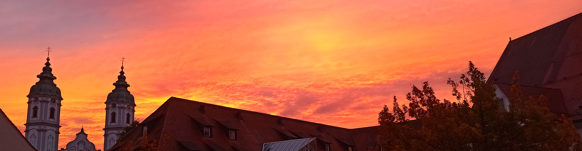 Sonnenaufgang über der Hofgartenklinik in Bad Waldsee. Im Hintergrund zwei Kirchtürme.